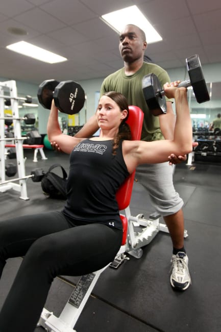 A woman lifting weights with a personal trainer