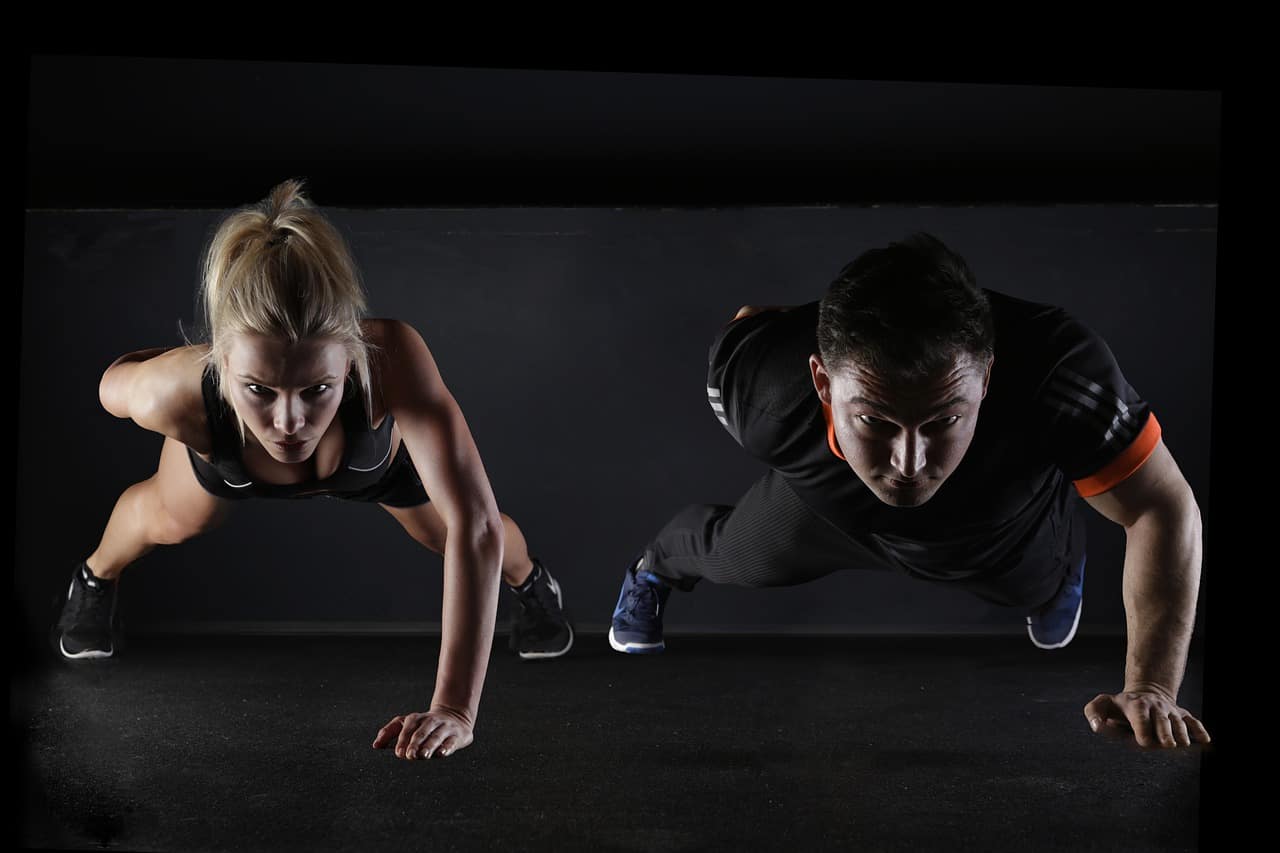 Fitness duo doing one arm push-ups