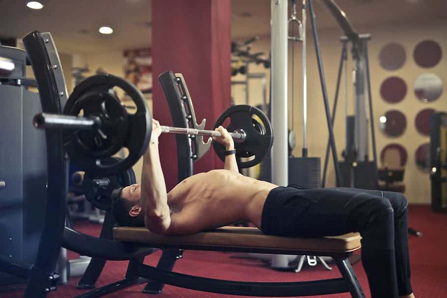 A man doing bench press with barbells at the gym