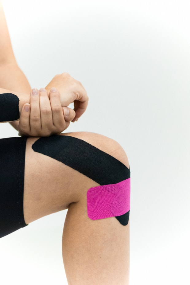 A person with kinesio tapes on his knees