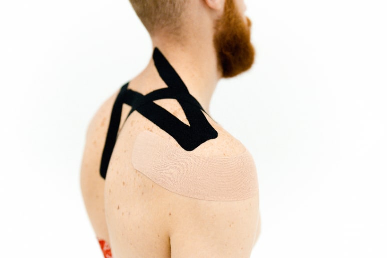 Kinesio tapes plastered on a man's upper back and shoulder