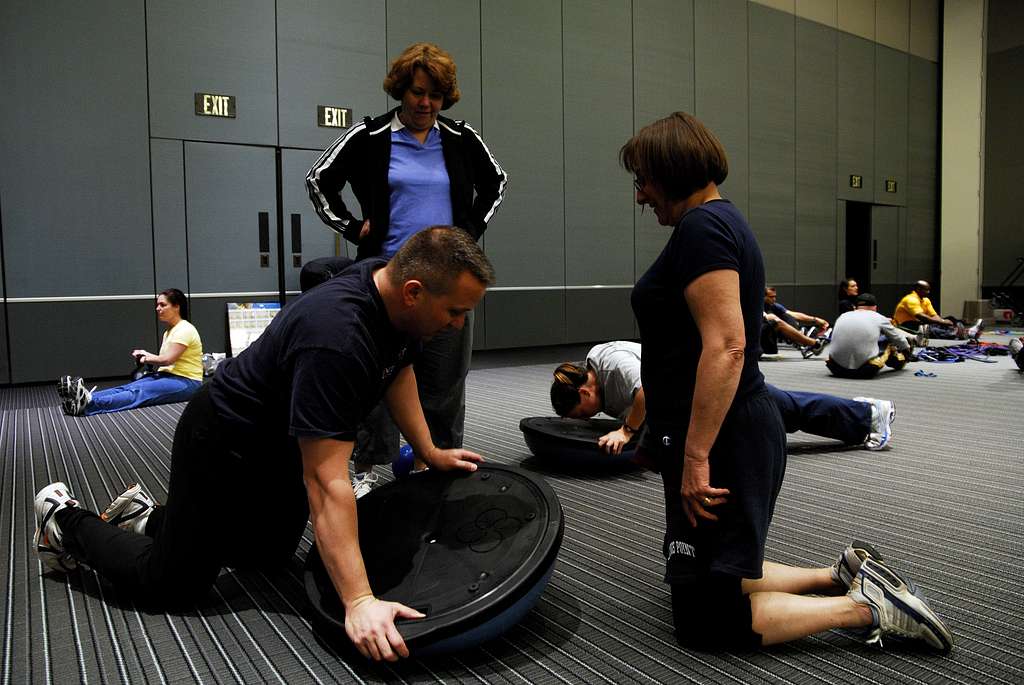A gym instructor demonstrating how a wobble board works