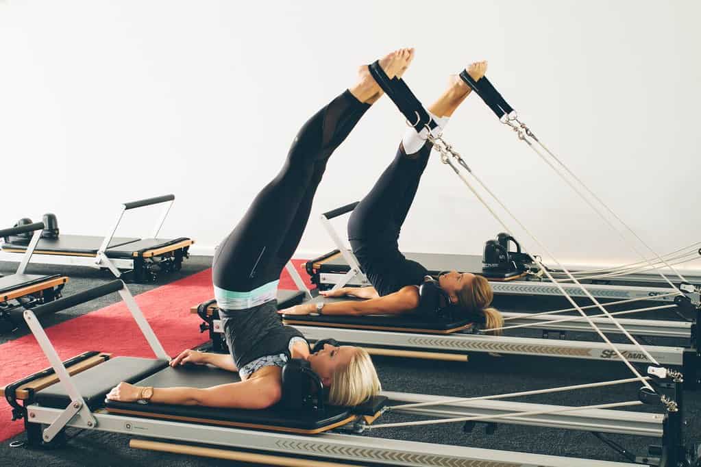 Women on Pilates reformers performing long spine exercise