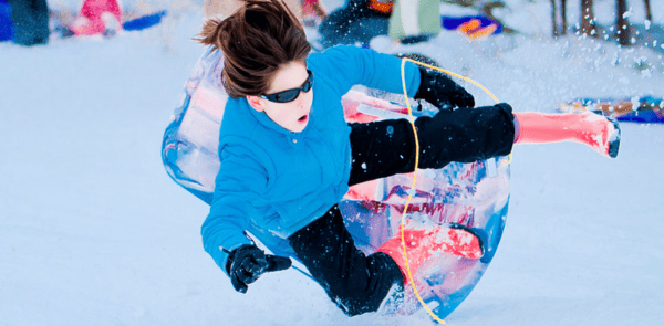 Woman slipping from a snowboard while sliding downhill, showing the risk of winter sports injuries.