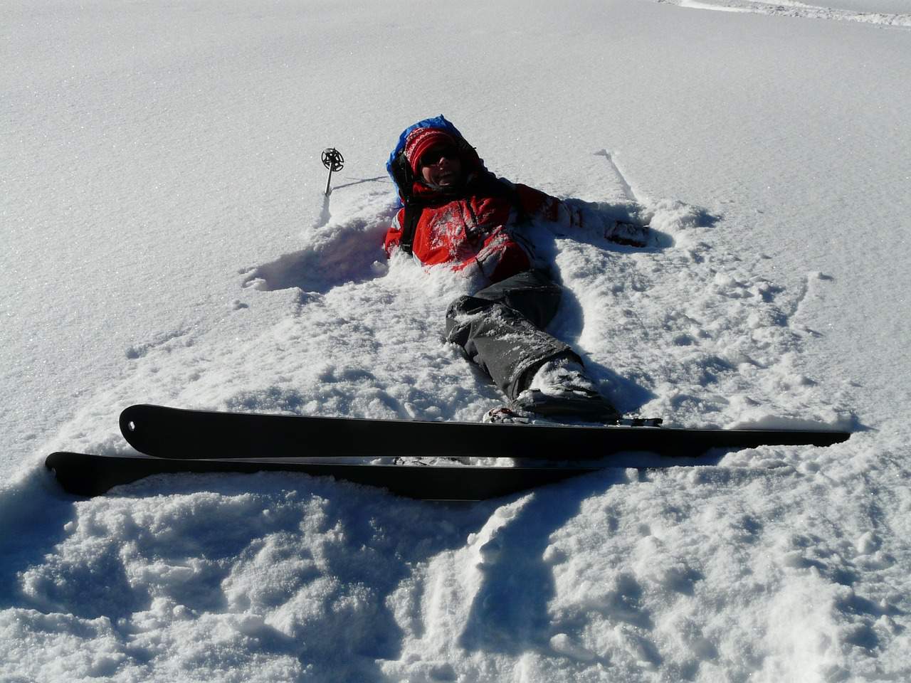 Fallen skier on snow, wearing winter gear and lying on a snowy slope.