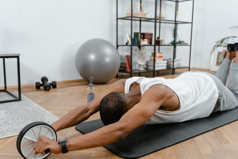 A man doing an ab workout at home using an abdominal roller wheel.