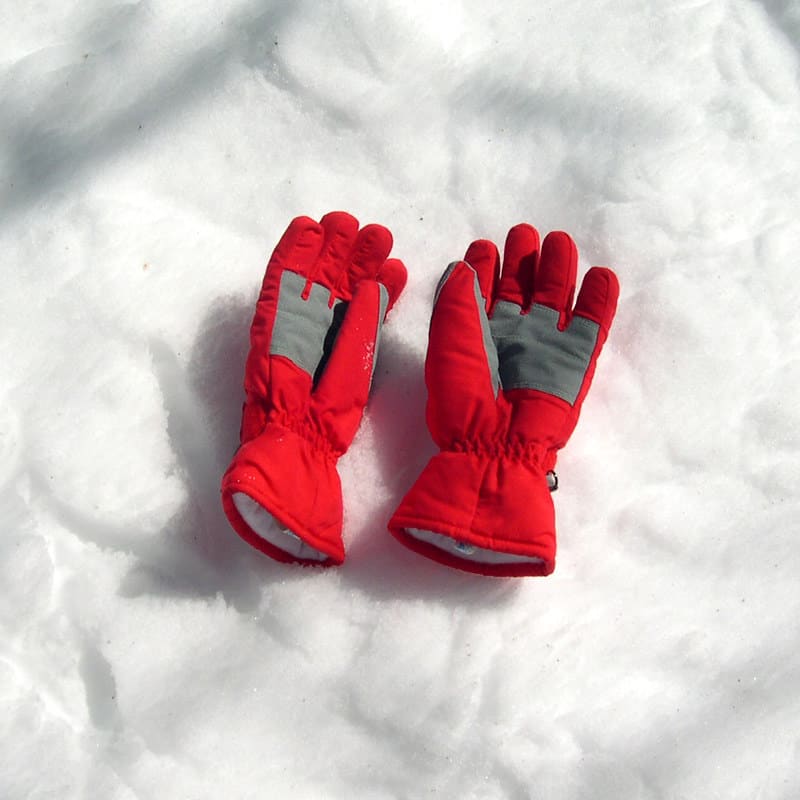 Red ski gloves resting on the snowy surface.