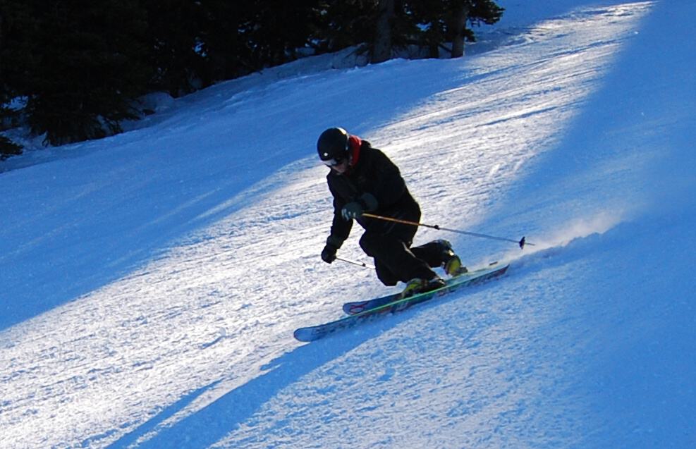 A skier skiing downhill, with their right leg slightly bent, almost losing their balance.