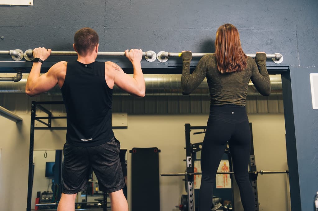 Fitness models demonstrating pull-up bar exercises.