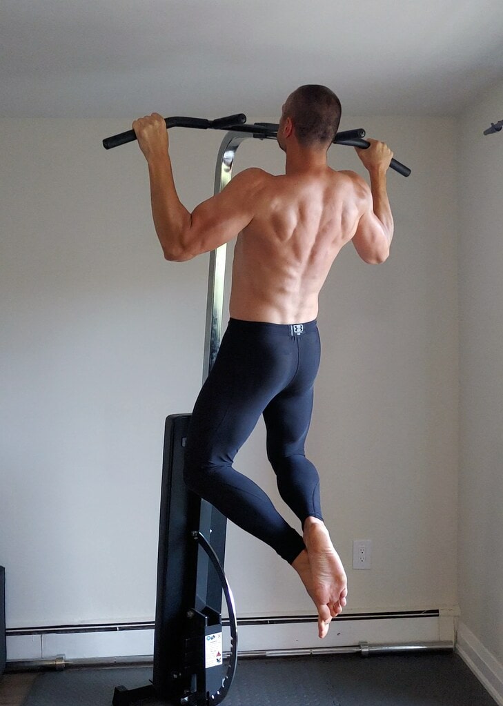 Man performing back workout at home using a pull-up bar.